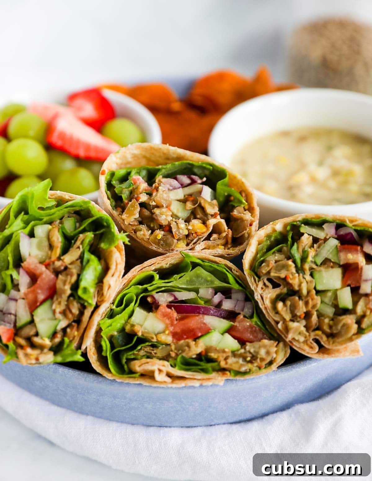 Four wraps with fresh vegetables and lentils in a blue dish
