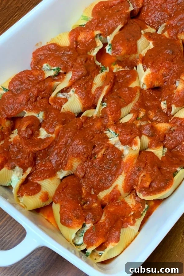 spinach, cheese and sausage stuffed shells covered in red pasta sauce in a white 9x13 pan