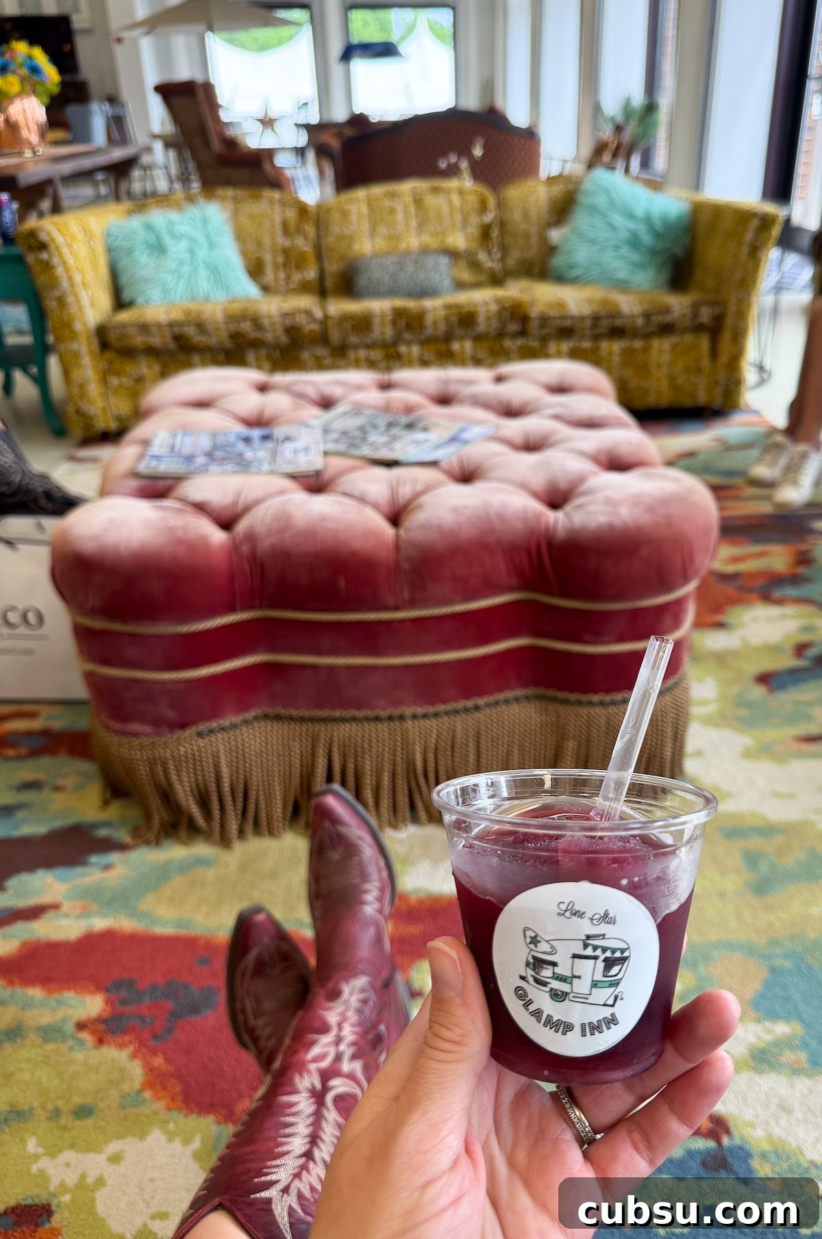 A cup of frozen sangria from the Lone Star Glamp Inn during Antiques Week with vintage plush seating in the back.